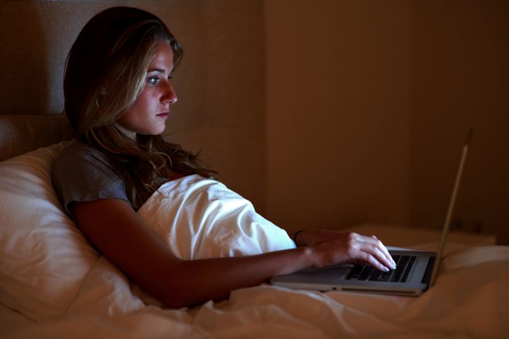 Portrait of a cute young girl using laptop while lying on the bed at home