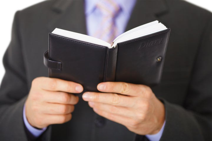 Businessman reading a small notebook with the inscription - Diary