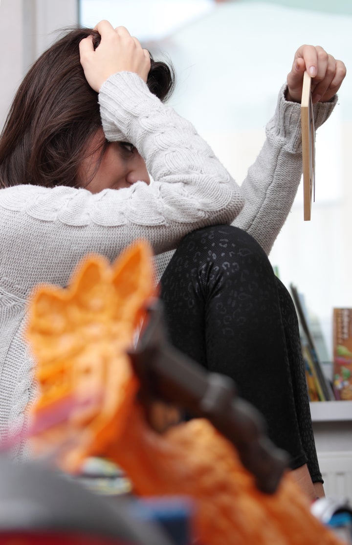 Young sad woman (mother) sitting in children room looking on photo frame (lost of child concept)