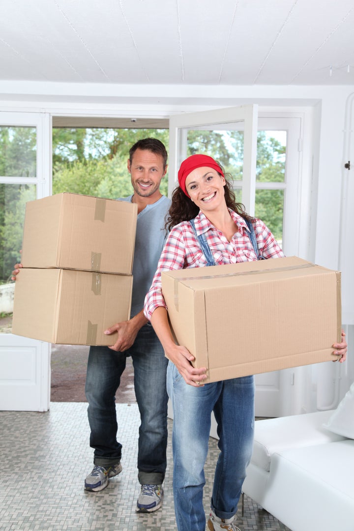 Couple holding boxes in their new home