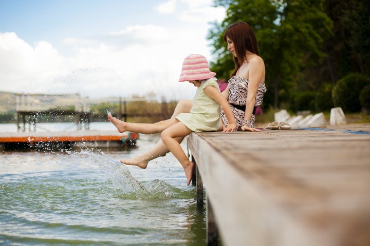 Young mother and her daughter splashing in the lake