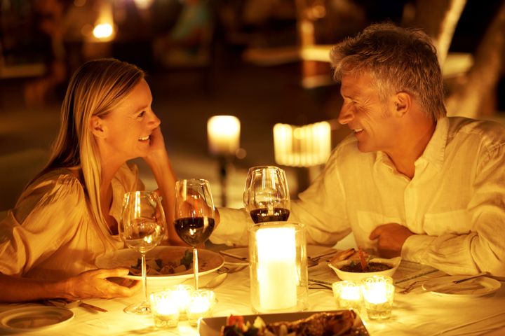 Mature couple enjoying candlelight dinner in a restaurant toasting wine glasses