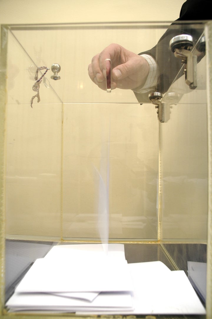 ballot box and hand putting a...