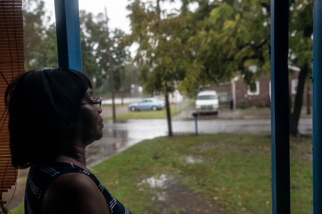 Shirley Griffin, 65, watches the floodwaters from her front porch. The water reached the curb in front of her home early Friday morning before it began to slowly recede.