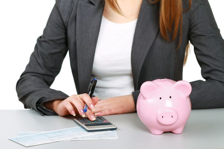 Young woman with a piggy bank and using a calculator