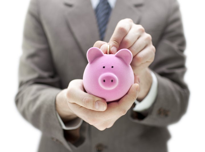 Businessman putting coin into the piggy bank