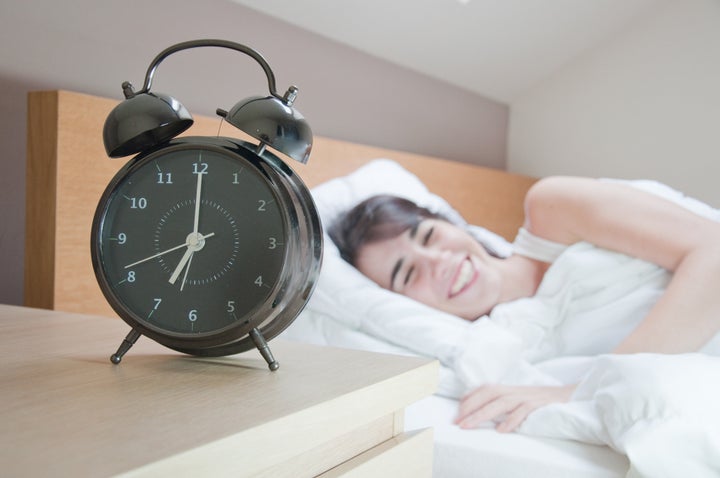 young woman with alarmclock on...