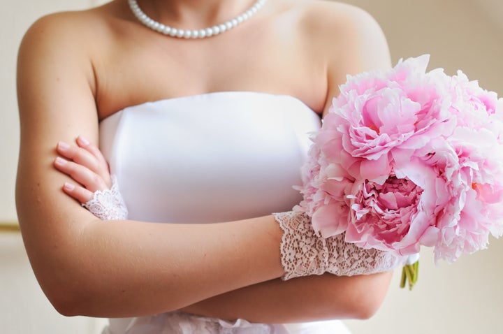 Discontented bride - young woman holding beautiful wedding flowers bouquet (peony)