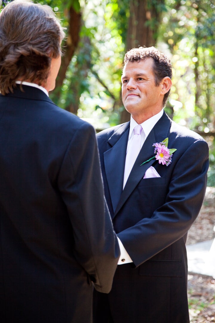 Handsome hispanic groom marrying his same sex partner in an outdoor wedding ceremony.