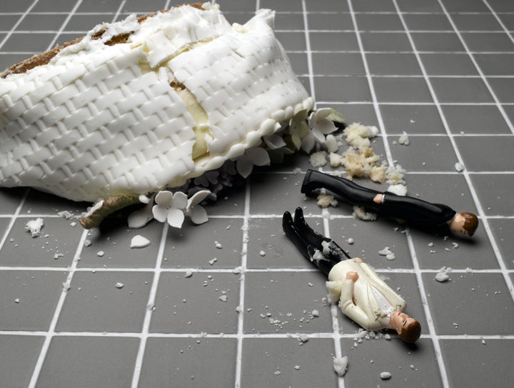 Two groom figurines lying at destroyed wedding cake on tiled floor