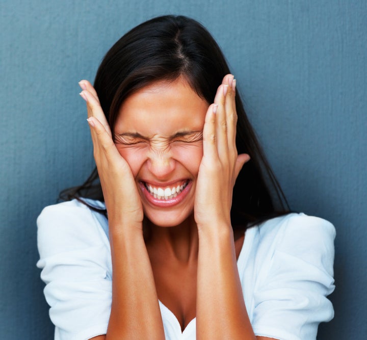 Woman with hands against cheeks against blue background