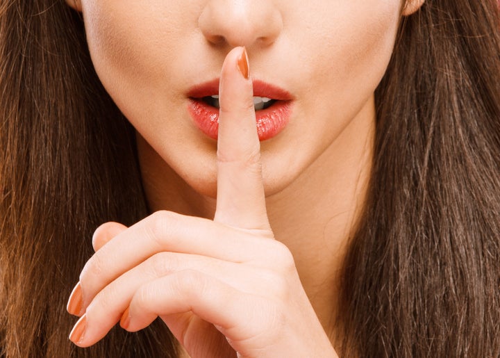 Mouth, of young beautiful brunette, having brought to mouth index ????, on red background.