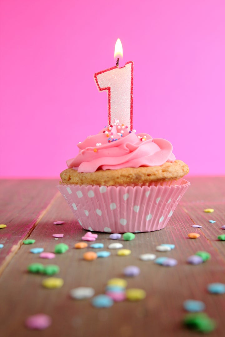 Number one birthday candle on a pink cupcake on a wooden table