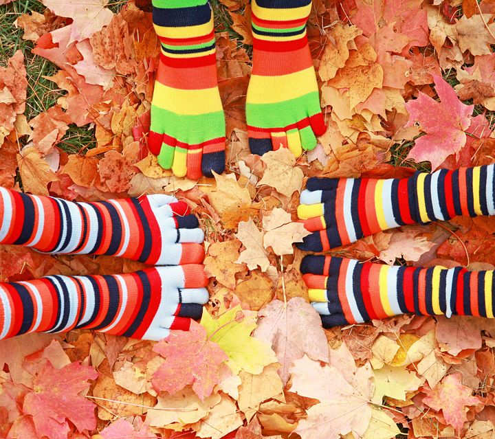 Three Children's Feet in Autumn Leaves