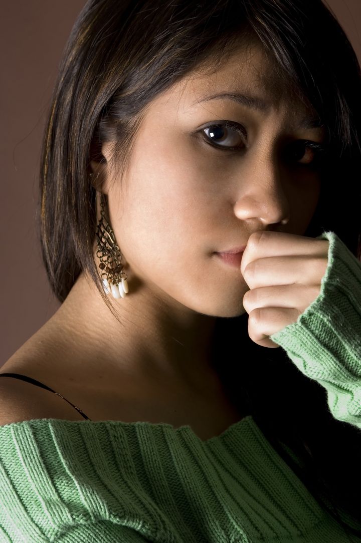 A moody portrait of a young woman in green jumper
