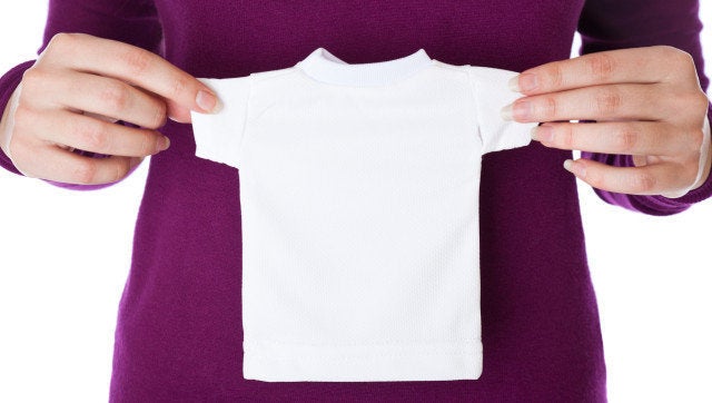 a woman is holding a small white T-shirt in her hands. isolated on a white background