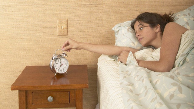 young woman setting alarm clock