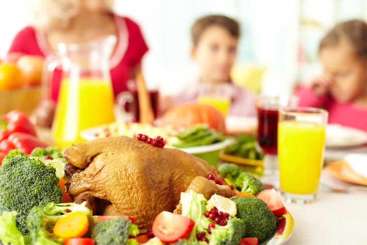 Close-up of roasted turley served with broccoli on background of siblings and woman