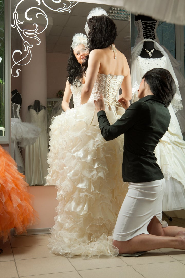 Women making adjustment to wedding gown in professional fashion designer studio