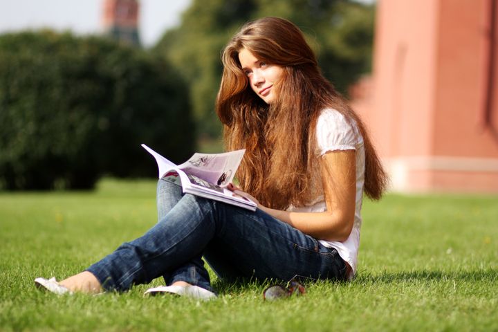 girl reading magazine in a park