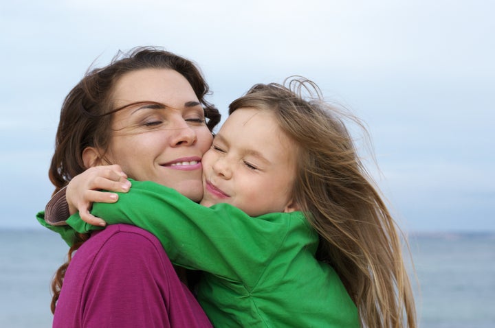 Happy mother and daughter embracing at beach.