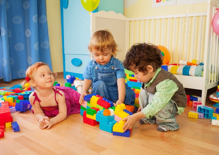 Kids playing with plastic blocks - two boys and girl