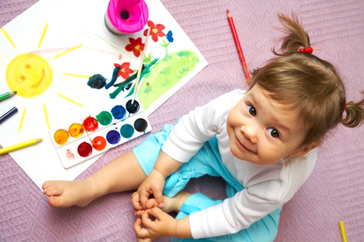 Little cute girl painting sun inside