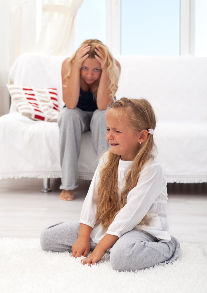 Little girl having a temper tantrum with her desperate mother in background