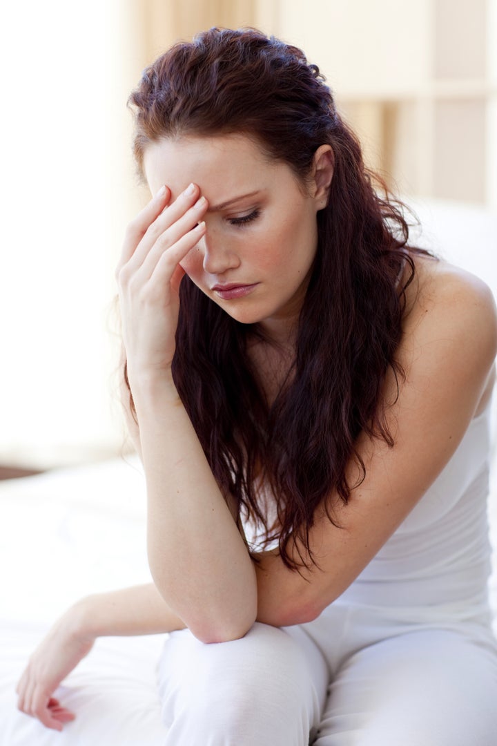 Beautiful woman having a headache sitting in bed