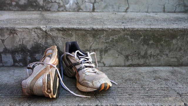 A pair of old used running shoes on cement steps.