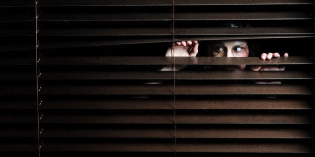 Mysterious woman pulls the blinds apart to see the outside world