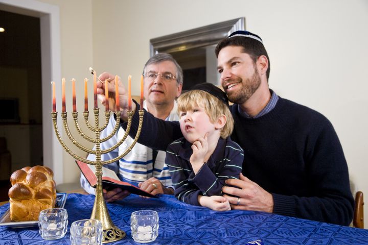 Three generation Jewish family lighting Chanukah menorah