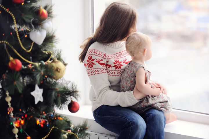 Mother with baby sitting by the window. Christmas decorations. On Christmas, waiting for a miracle. A woman with a child looking out the window.