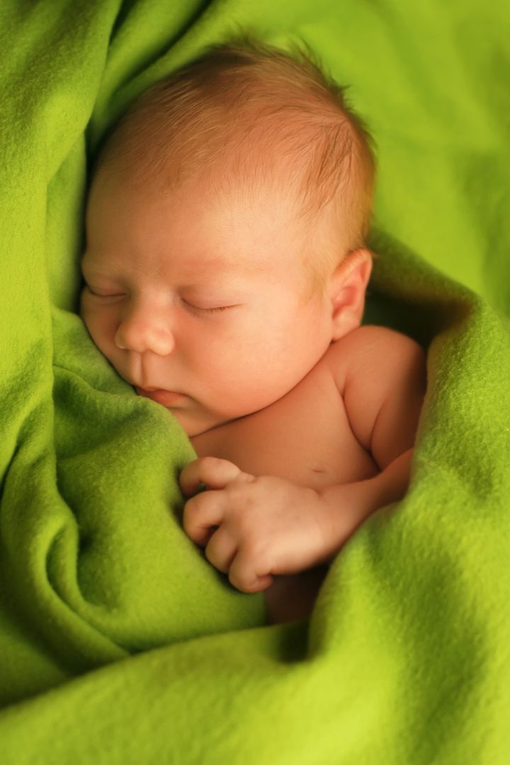 Newborn baby sleeping on a green blanket