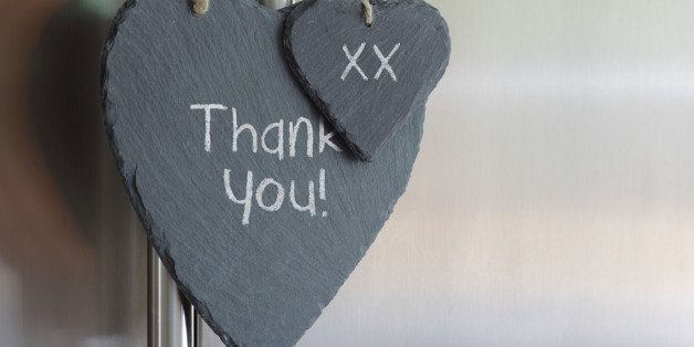 Thank you note written in chalk on a slate heart hanging on a refrigerator door