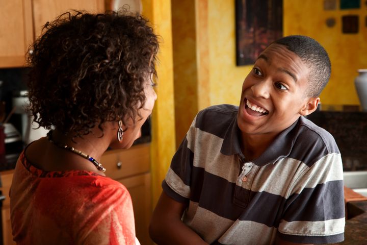 Attractive African-American woman and teen laugh in kitchen