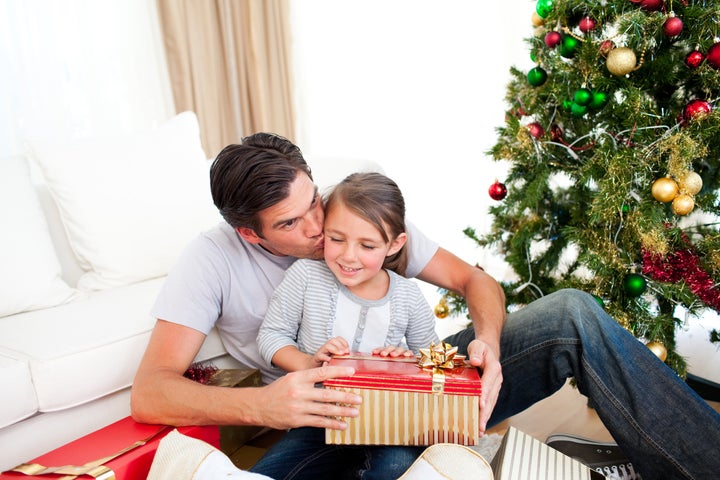 Father kissing his little daughter after giving her a Christmas gift at home