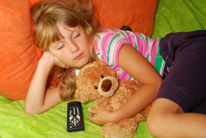 young girl which fell asleep with her teddy bear watching tv