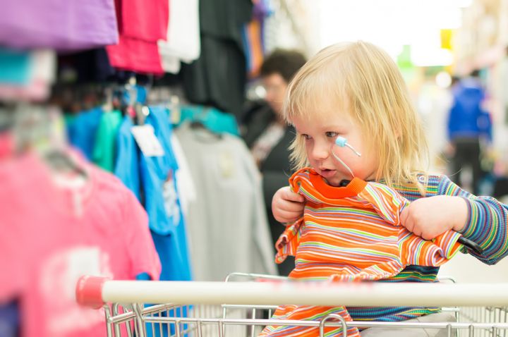Adorable baby on cart choose clothes in supermarket