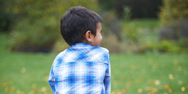 Male toddler in the garden sitting on pumpkin