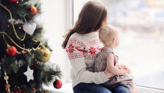 Mother with baby sitting by the window. Christmas decorations. On Christmas, waiting for a miracle. A woman with a child looking out the window.