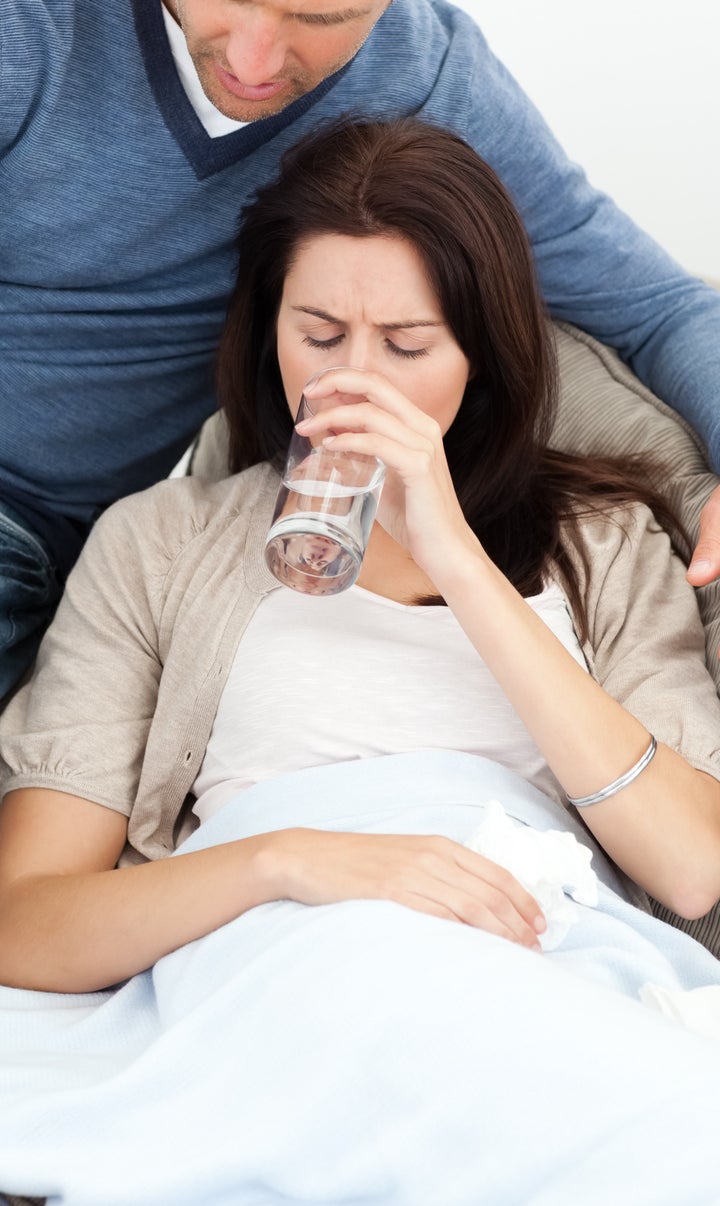 sick woman drinking water lying ...