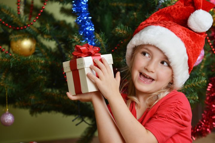 Pretty little girl in santa cap near Christmas tree