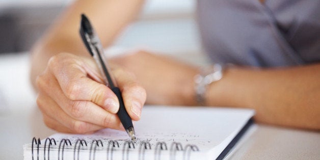 Cropped image of hand of young woman taking notes