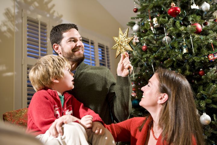 Family with child by Christmas tree, dad holding star