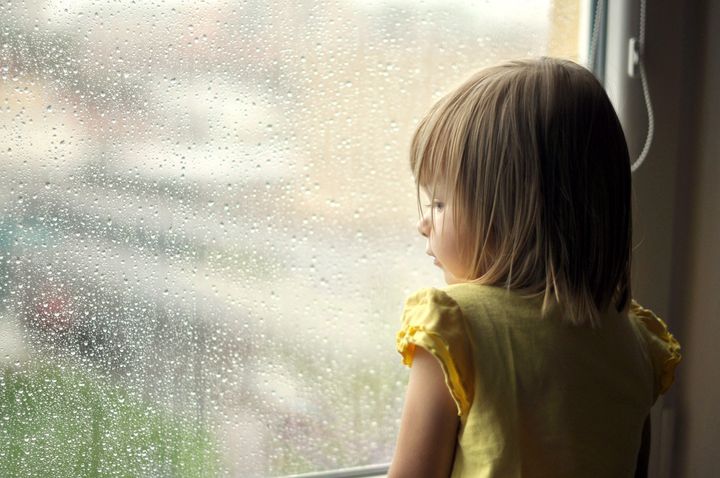 young girl looking from window