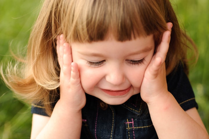 Little girl's face with hands and smile. Close up soft portrait on nature. Shalllow DOF.