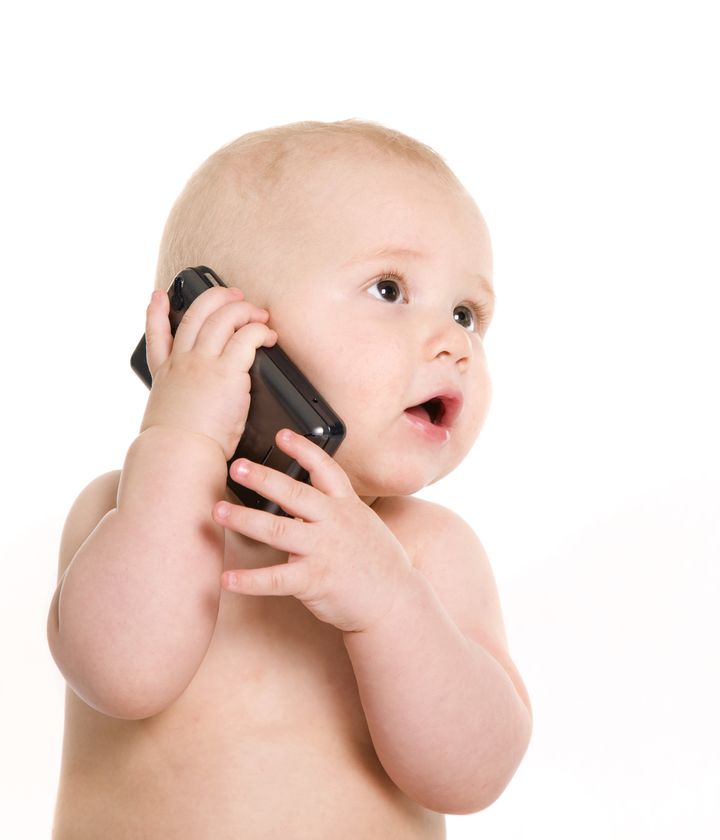 Portrait of pretty baby talking on mobile phone. Isolated over white