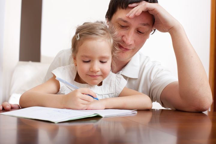 Father helping daughter doing homework. Parent with child writing