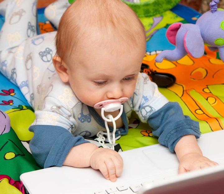 Baby boy with interest works with (computer) laptop